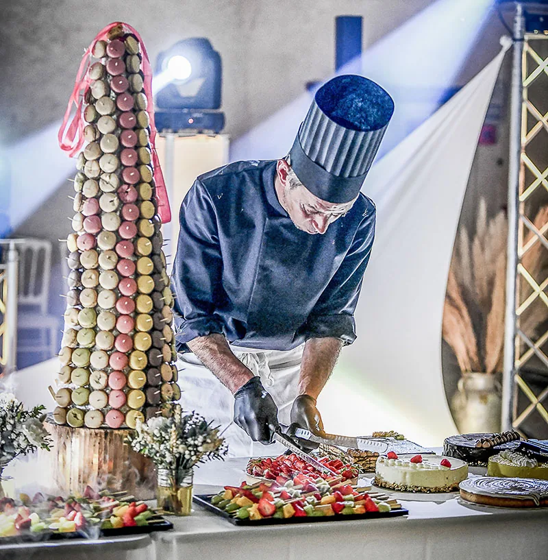Chef pâtissier devant une pièce montée de macarons